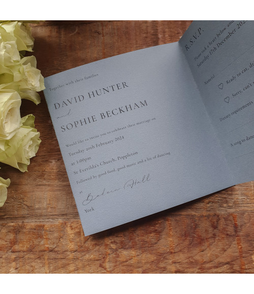 Close-up of personalised dusty blue wedding stationery with premium card finish