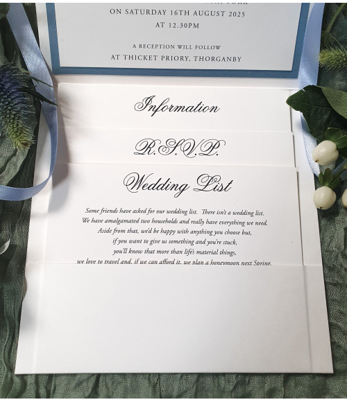 Layered pale blue wedding invitation set with premium inserts and satin ribbon detailing