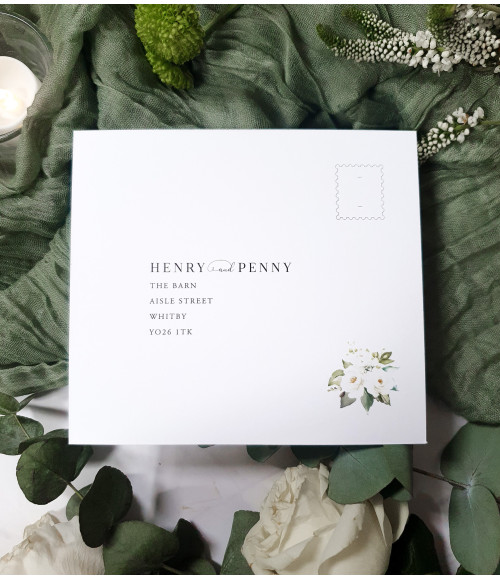 Close-up of white rose wedding invitation with textured card and elegant print detail