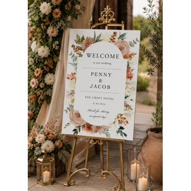 A1 floral wedding welcome sign displayed on a gold easel with elegant peach, blush and sage flowers at a romantic wedding venue.