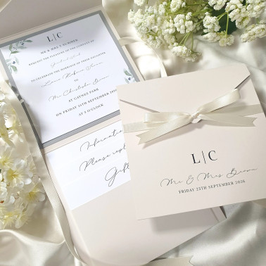 Ivory pocketfold wedding invitation with satin ribbon and personalised monogram displayed closed.