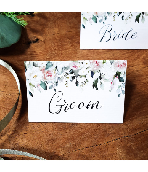 Elegant folded blush rose place name cards on textured card, romantic floral wedding stationery.