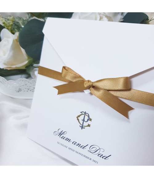Luxury gold wedding invitation with satin ribbon bow, personalised monogram and elegant pearl white card folder